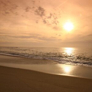 A beach with the sun setting in the background.