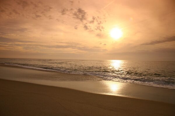 A beach with the sun setting in the background.